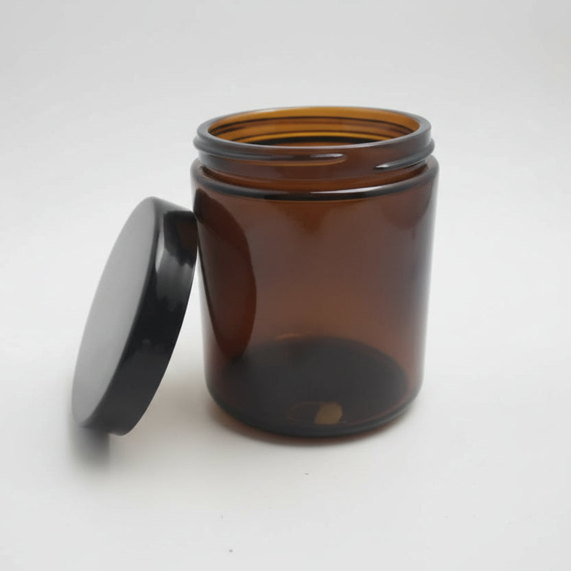 Amber glass jar with a black lid on a white background