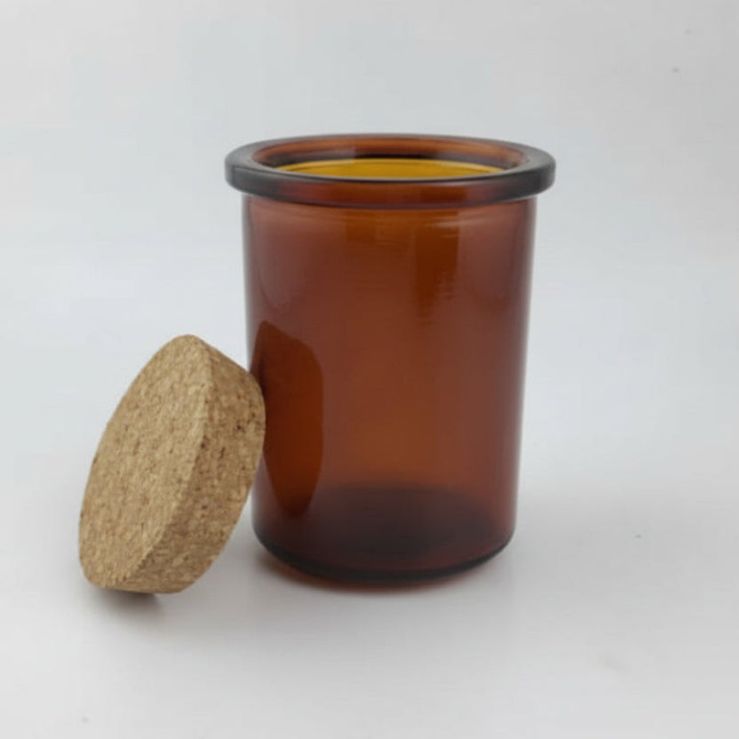 Amber glass jar with cork lid on a white background