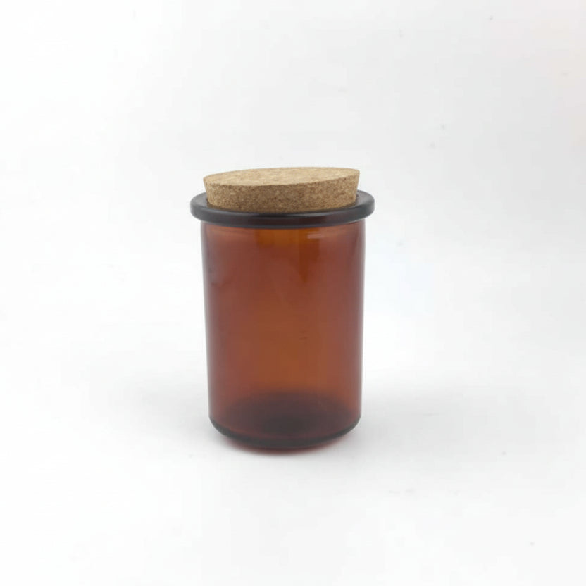 Amber glass jar with a cork lid on a white background