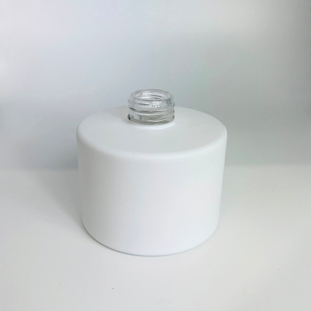 White cylindrical container with a metal cap on a white background