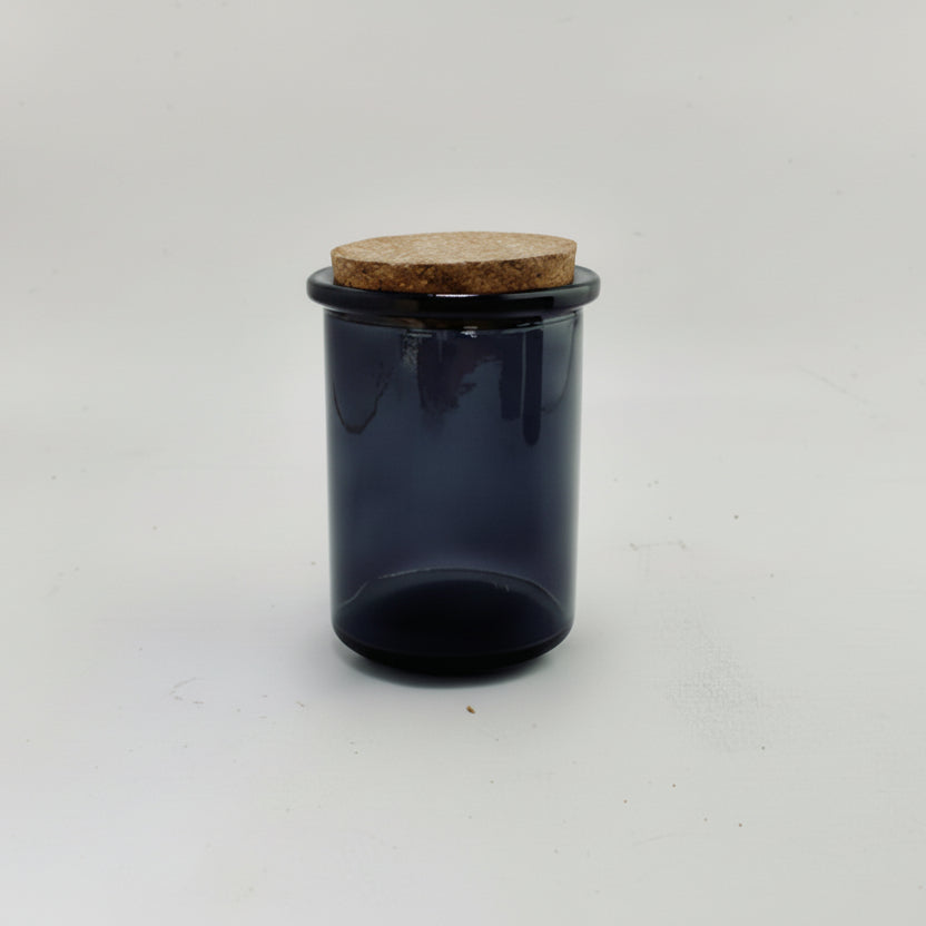 Black glass jar with a cork lid on a white background